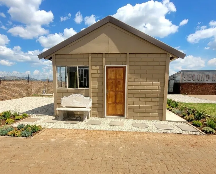 Compact precast unit with a pitched roof and timber door, finished with paving, planted beds and a bench at the entrance